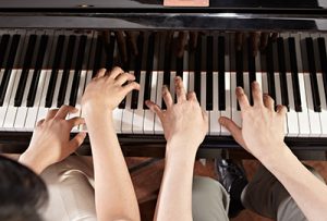 A photo of two sets of hands playing a piano to show how Context Marketing Communications works together with clients to build small business branding